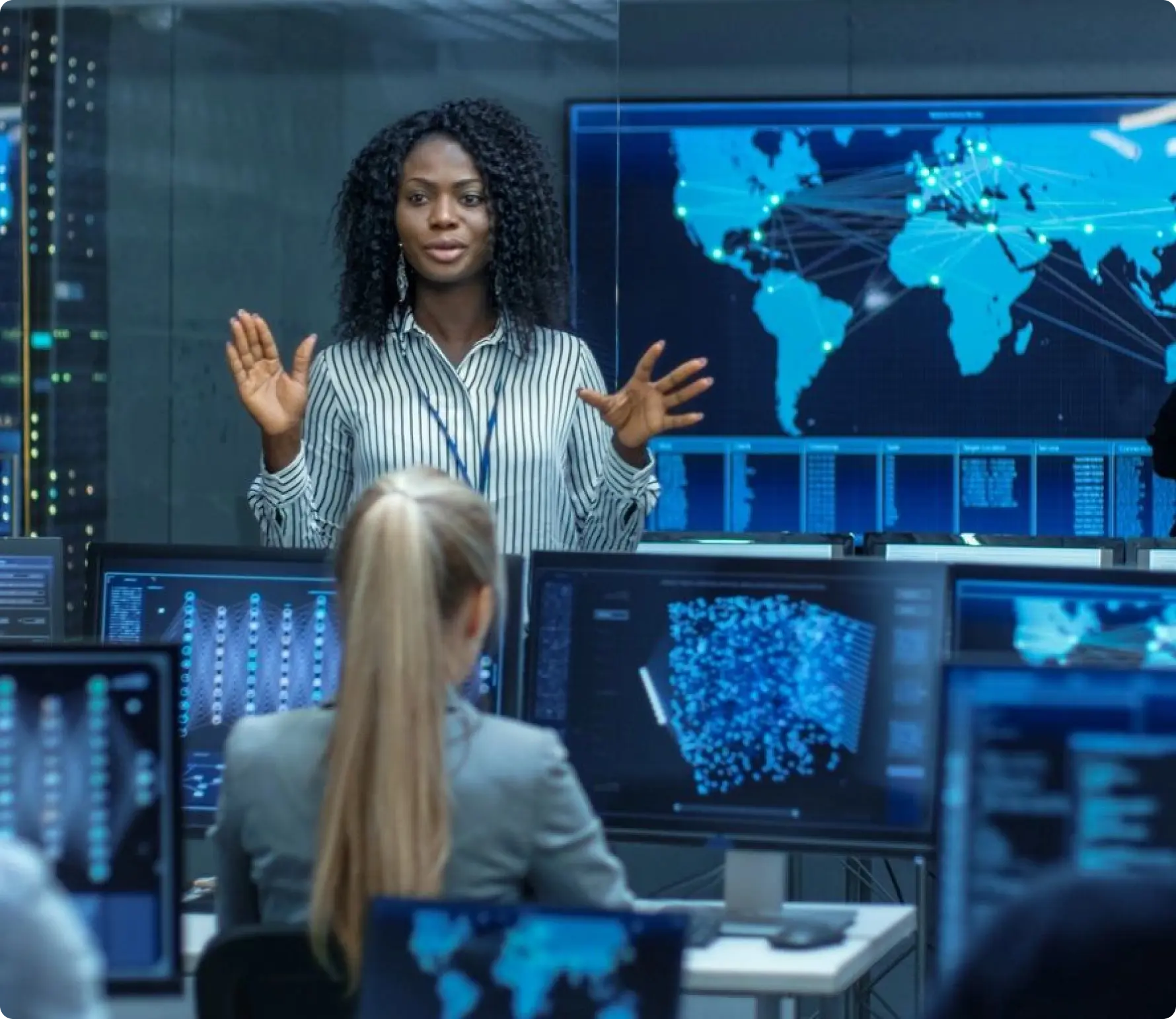 A woman standing in front of multiple monitors.